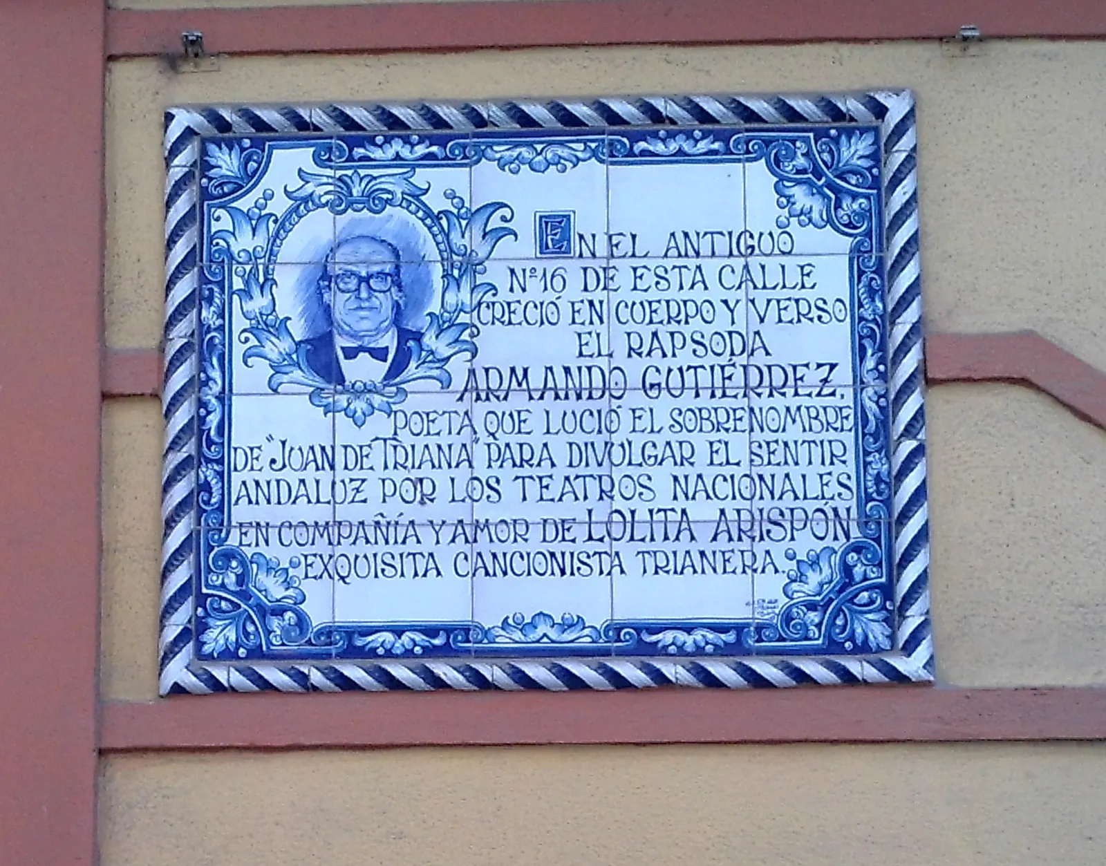A blue and white tile plaque on Calle Pureza with a portrait and a dedication to the poet Armando Gutiérrez