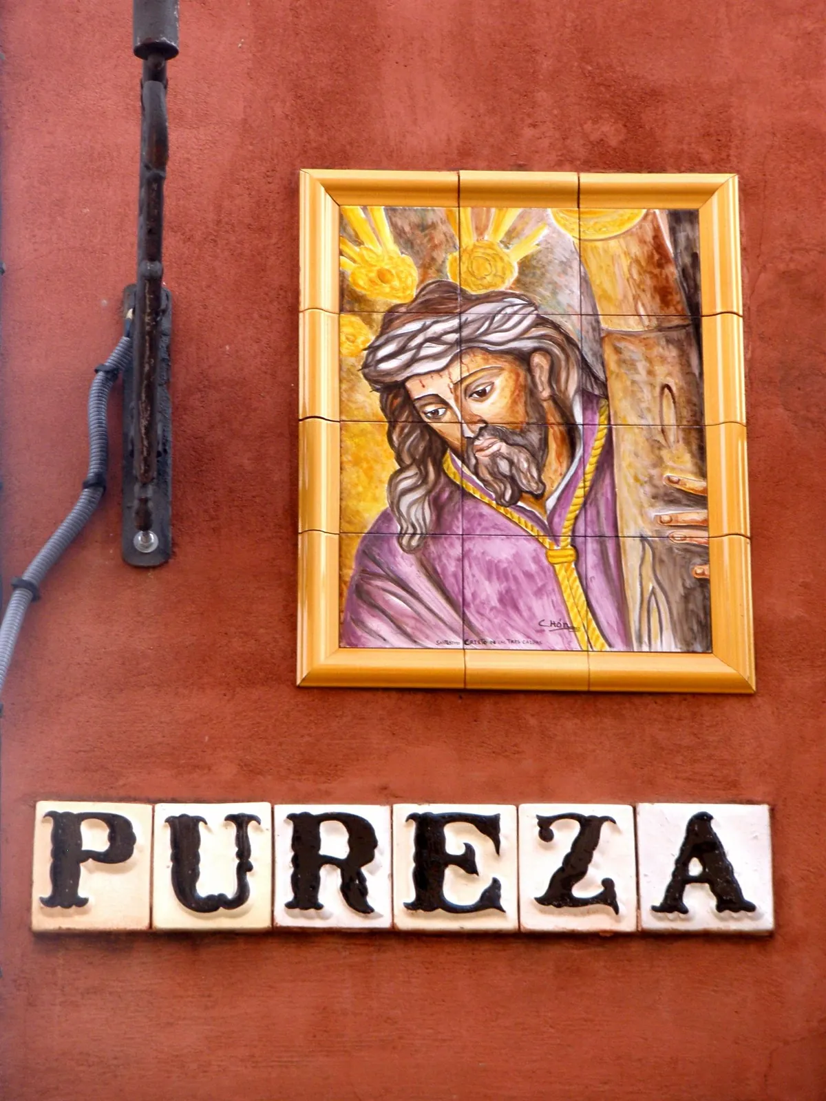 A ceramic image of Christ above the tiled Pureza street sign on Calle Pureza